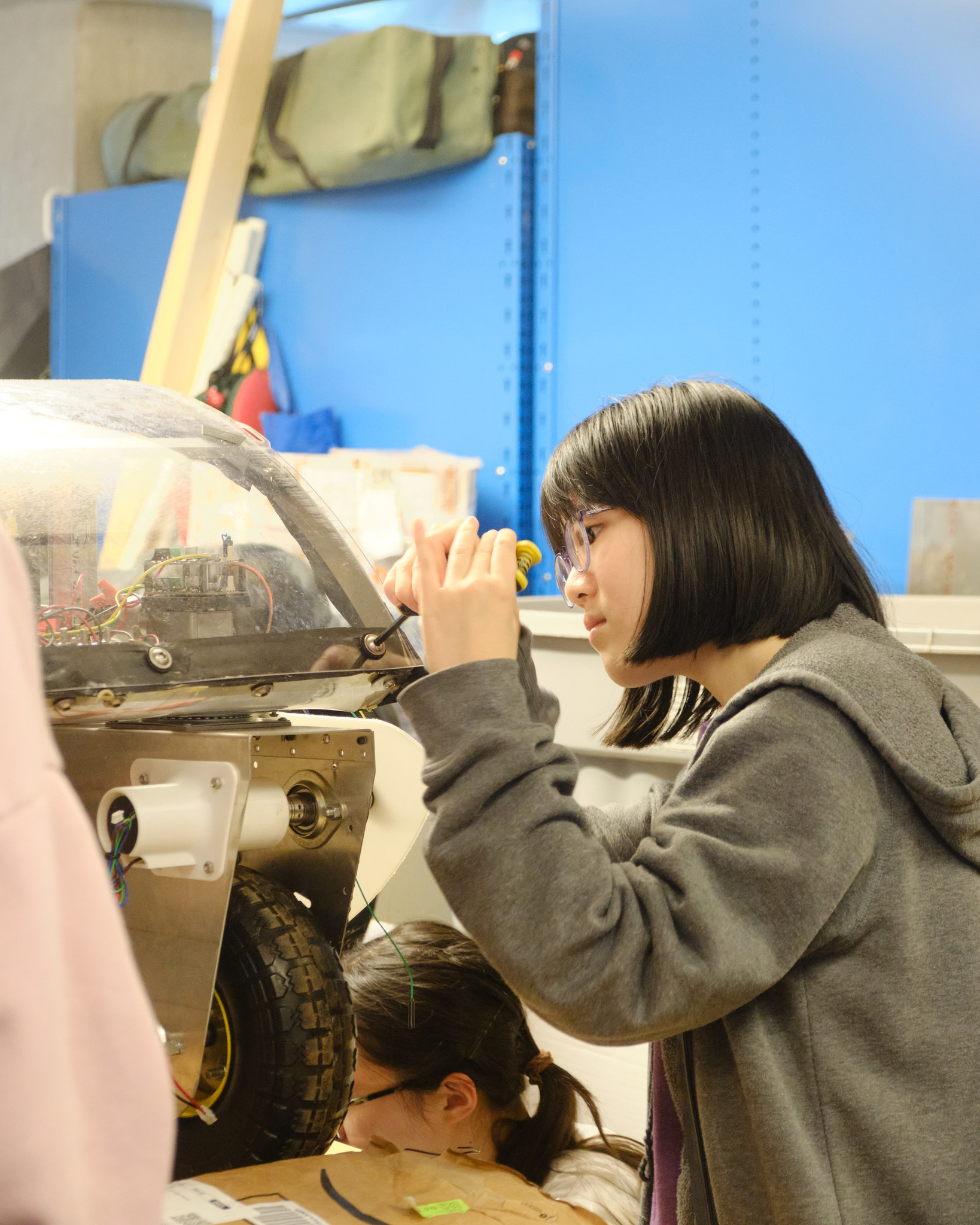 A team member adjusting the robot's wheel assembly with a screwdriver